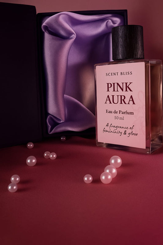 Perfume bottle labeled 'Pink Aura' with a purple fabric and pearls on a pink background